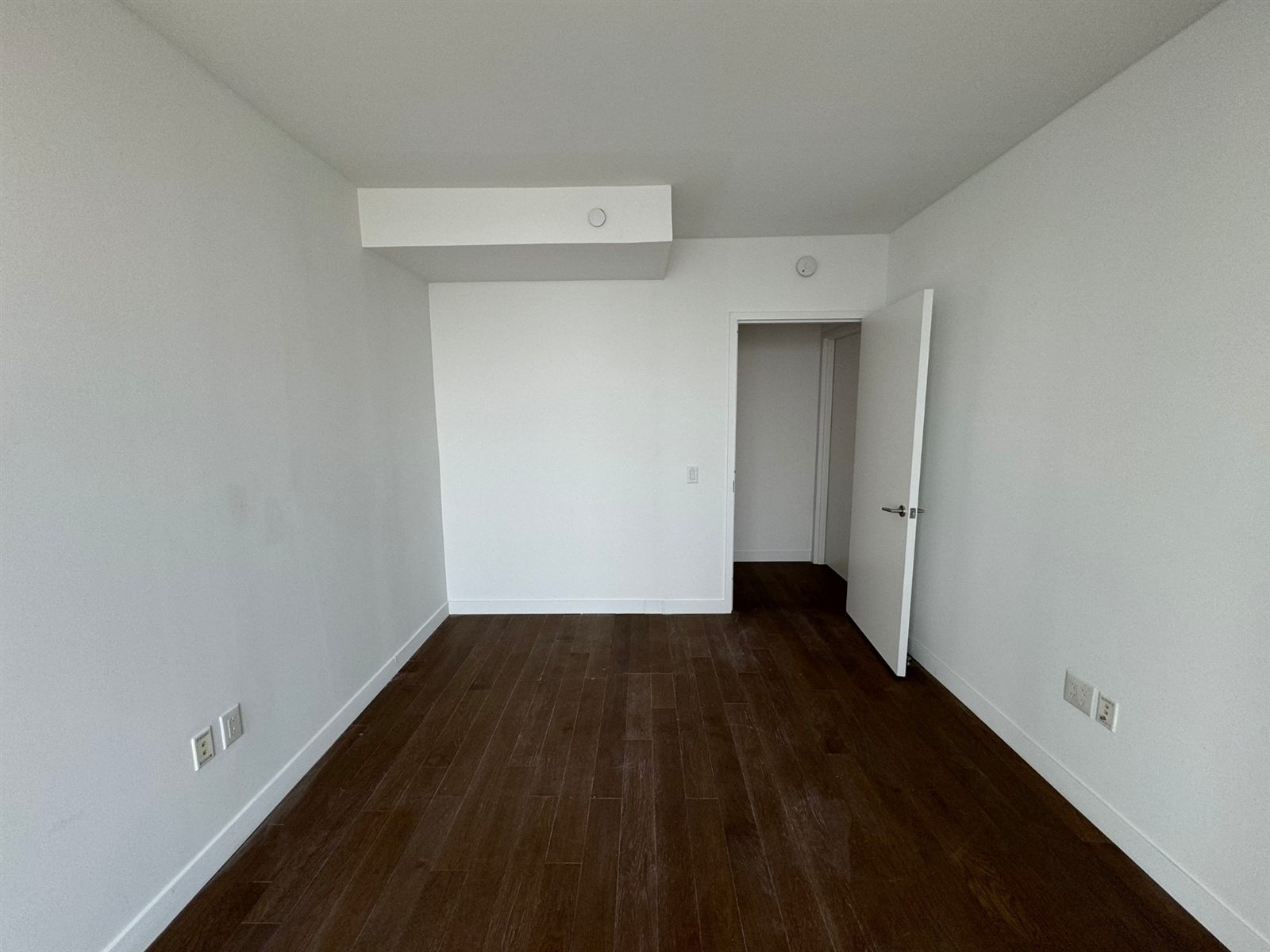 Freshly finished bedroom with white walls and dark hardwood floors