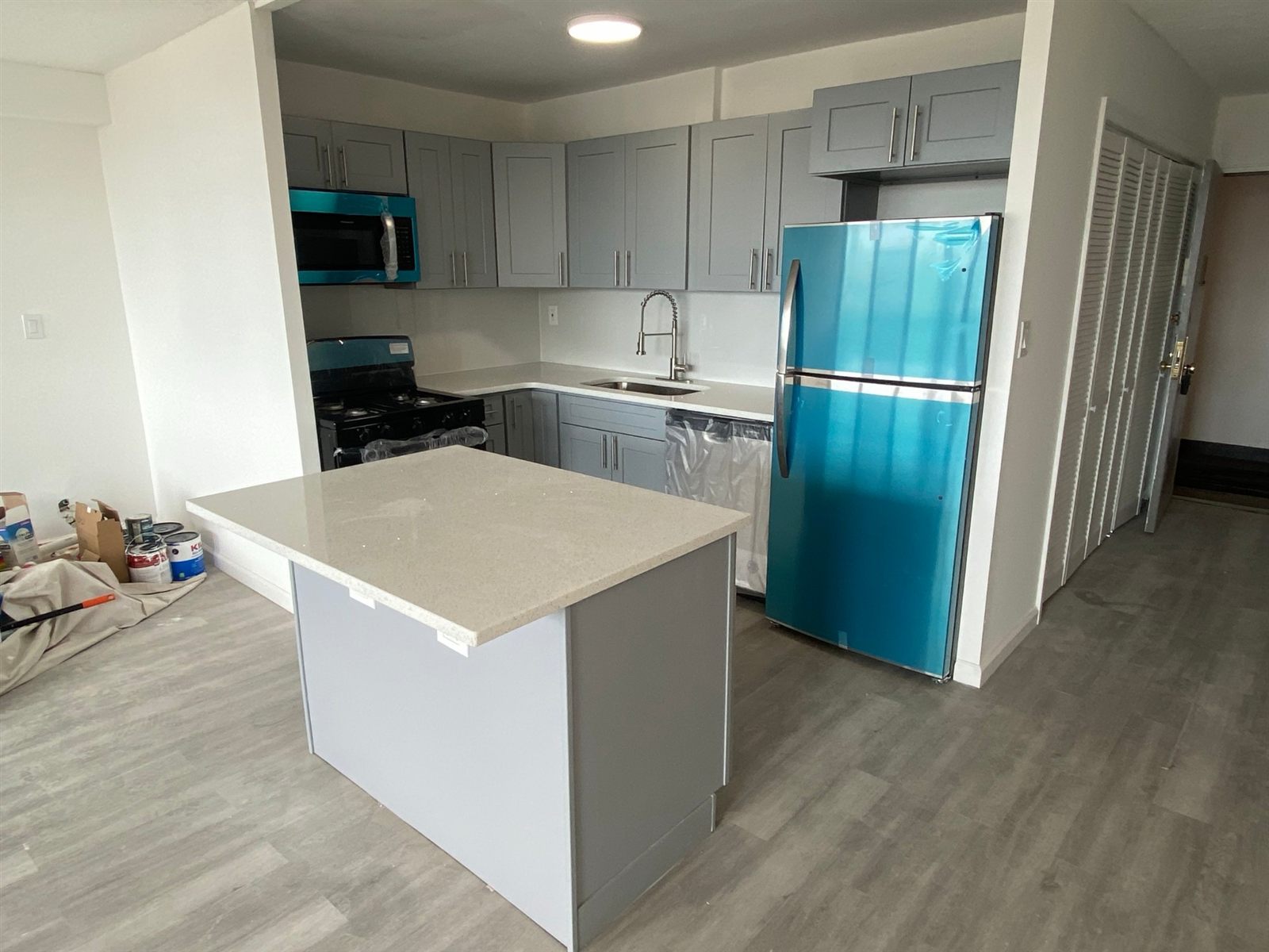 Kitchen with gray shaker cabinets, quartz counters, new island, and plank flooring