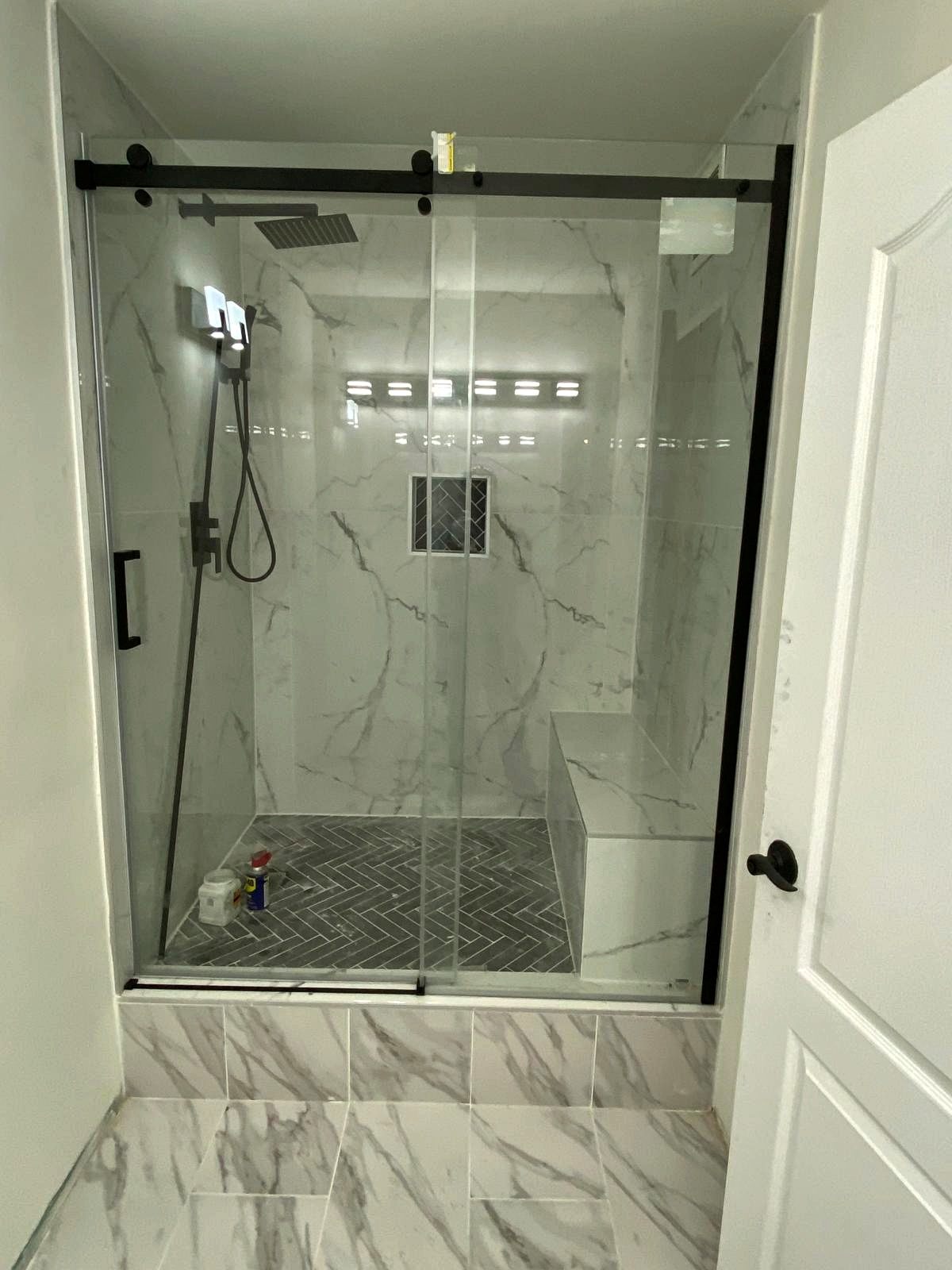 Walk-in shower with herringbone floor, bench, and black fixtures