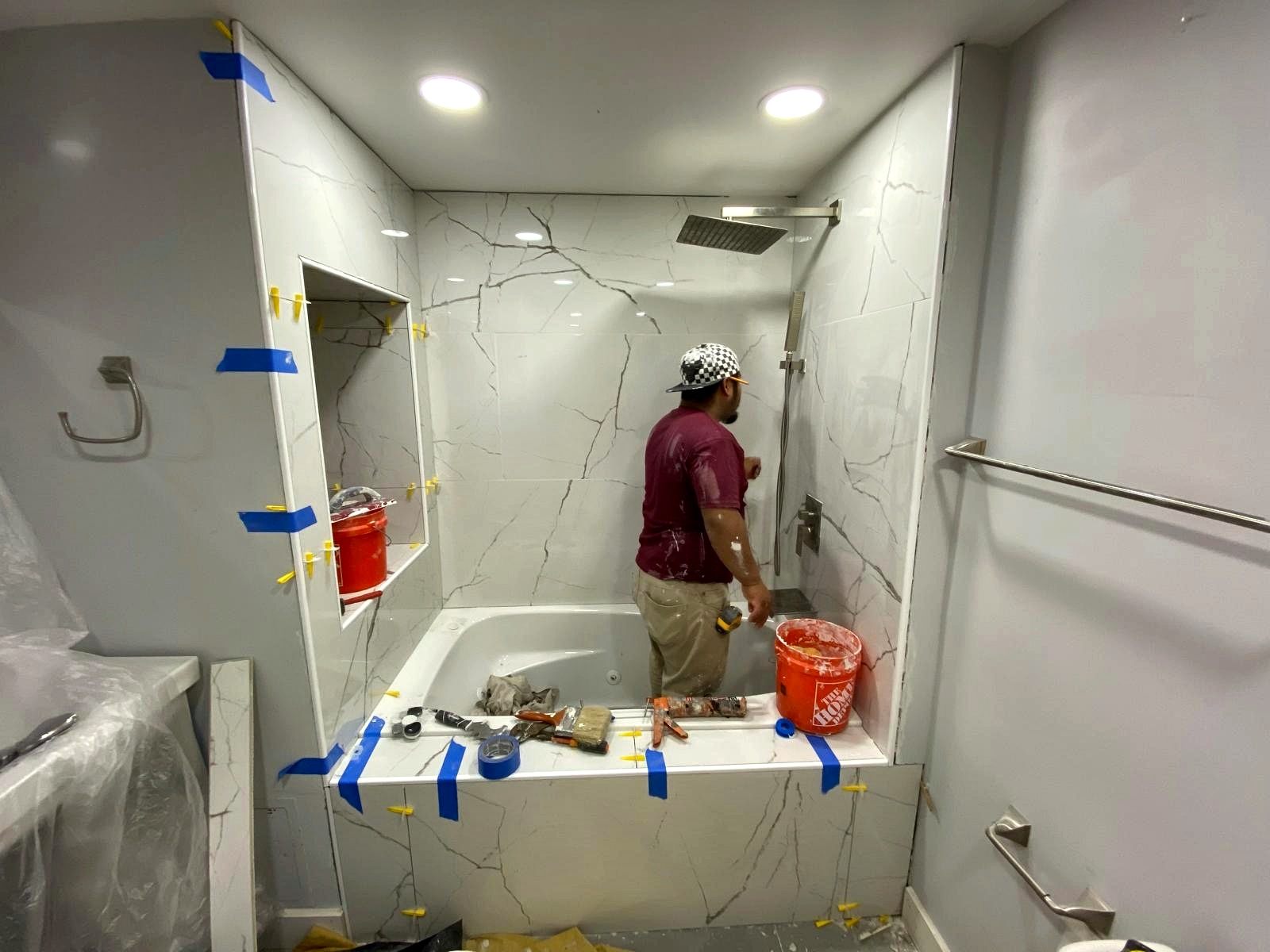 Penafort crew member installing large marble-look tile around a tub